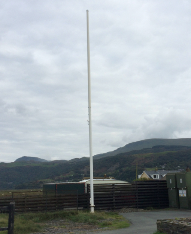 Photo of a large white flag pole in a field.