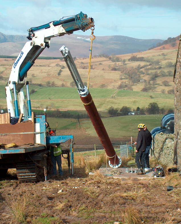 A timber clad pole getting lifted by a lorry.
