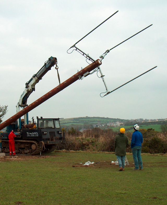 A large telegraph pole getting lifted by a lorry arm.